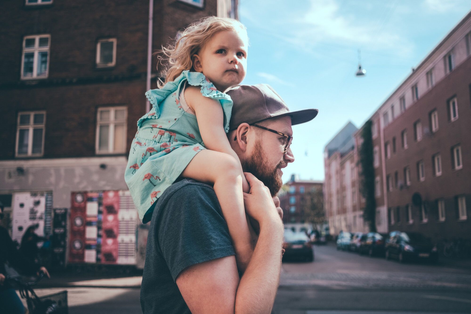 Side view of father carrying daughter on shoulders at city street